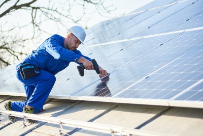 Solar-Installateur montiert Solarpanels auf dem Dach.